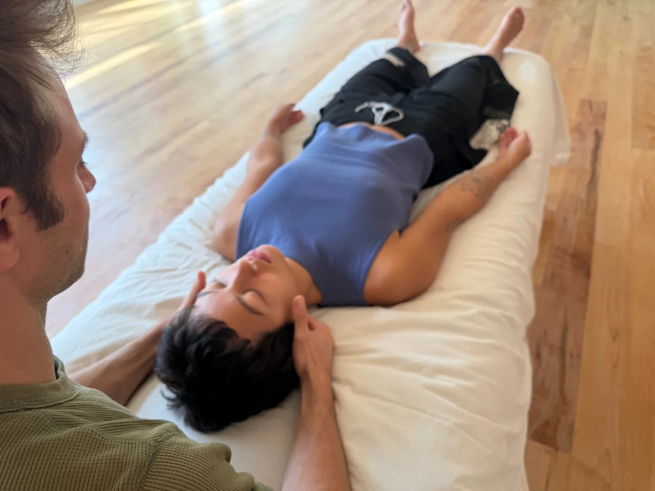John gently supporting a client’s head during a bodywork session.